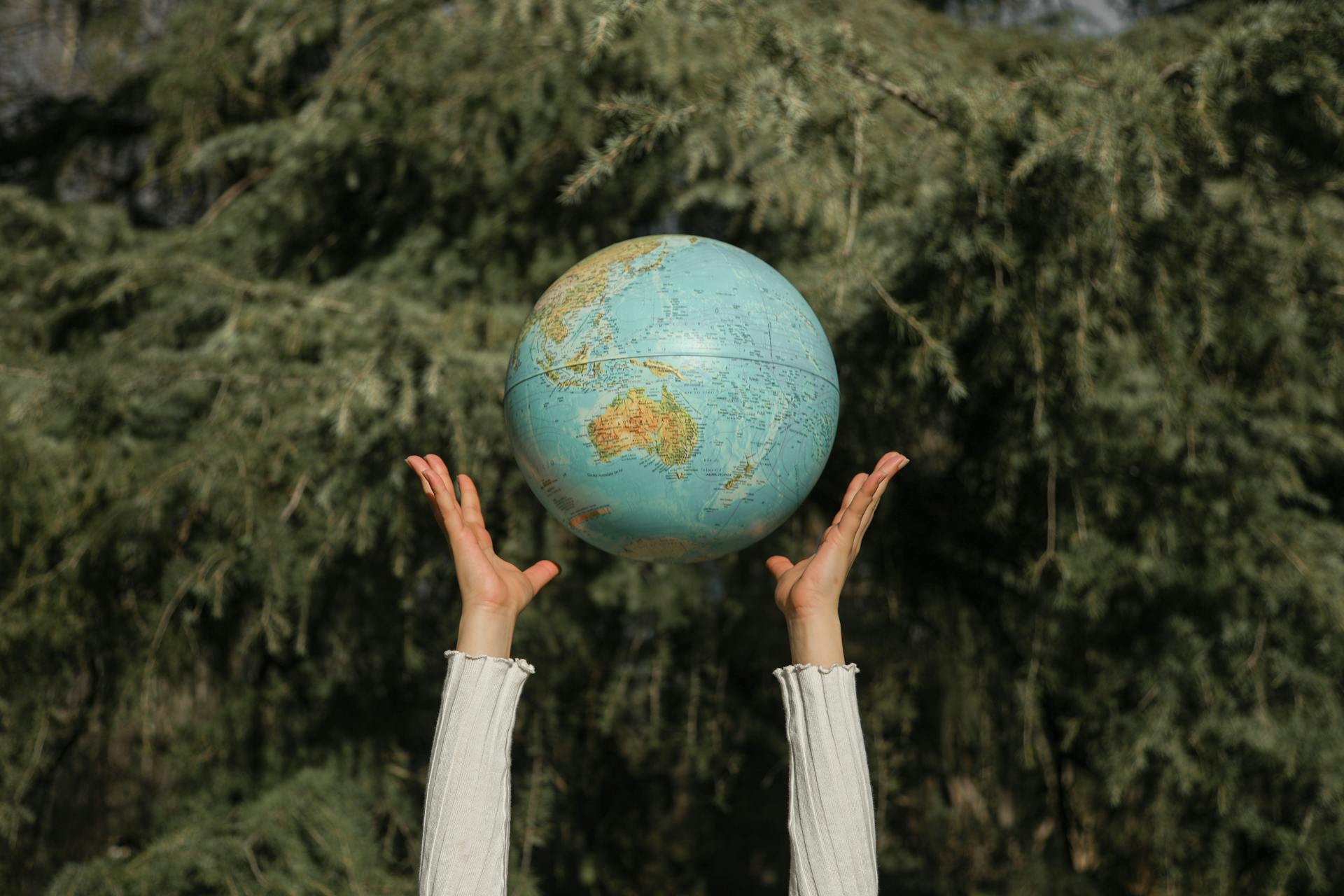 Two hands throwing a globe into the air